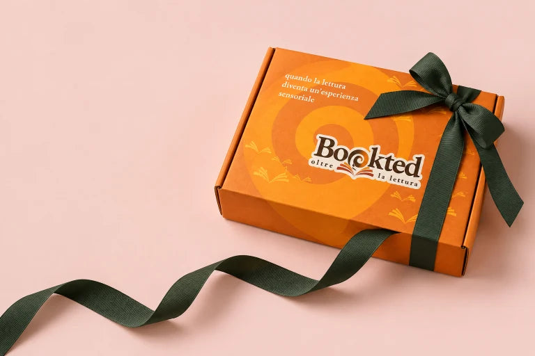 La confezione regalo Bookted arancione, con un nastro verde su fondo rosa.