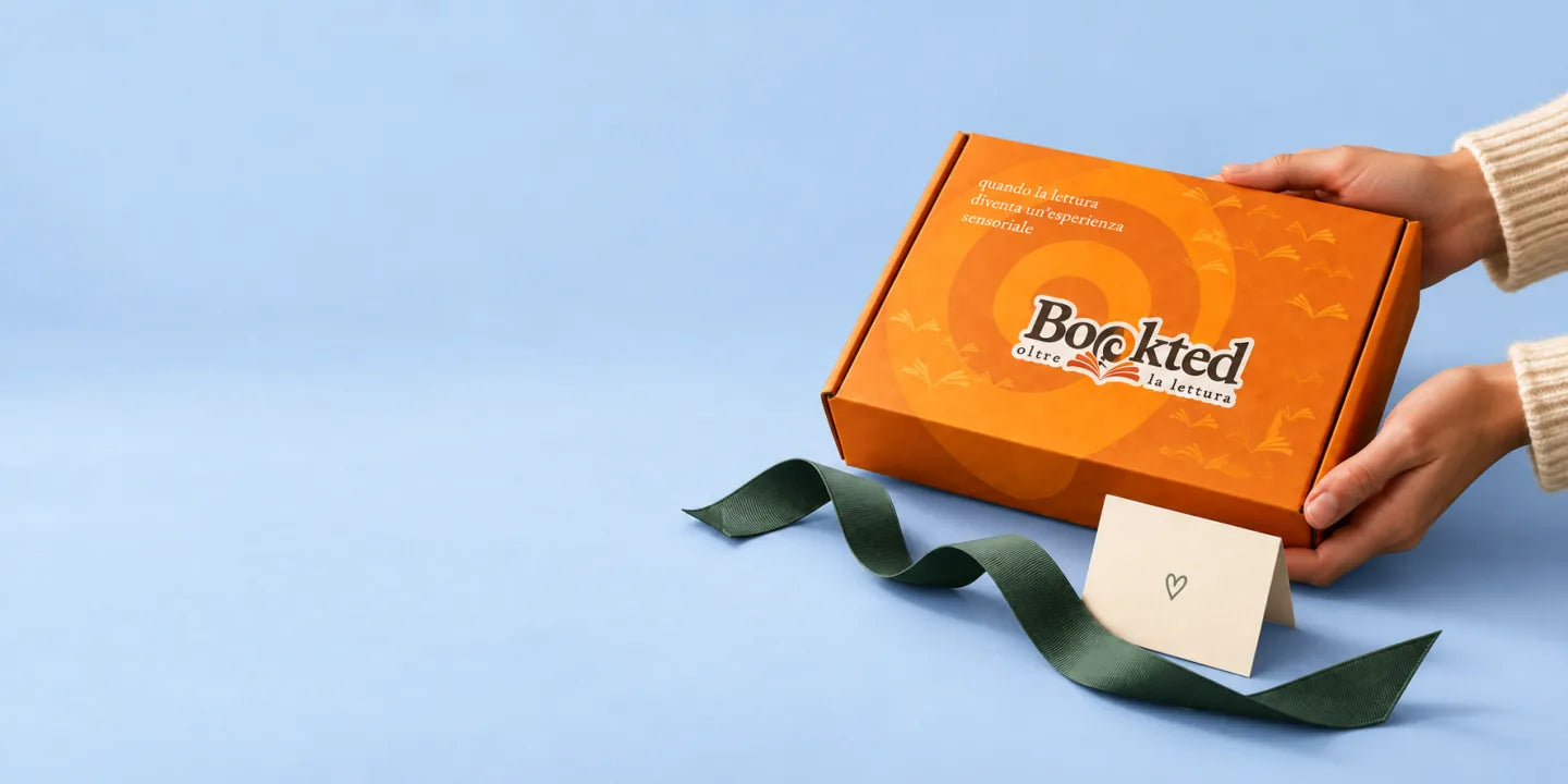 Un regalo Bookted tra le mani, con nastro verde e biglietto, su fondo azzurro